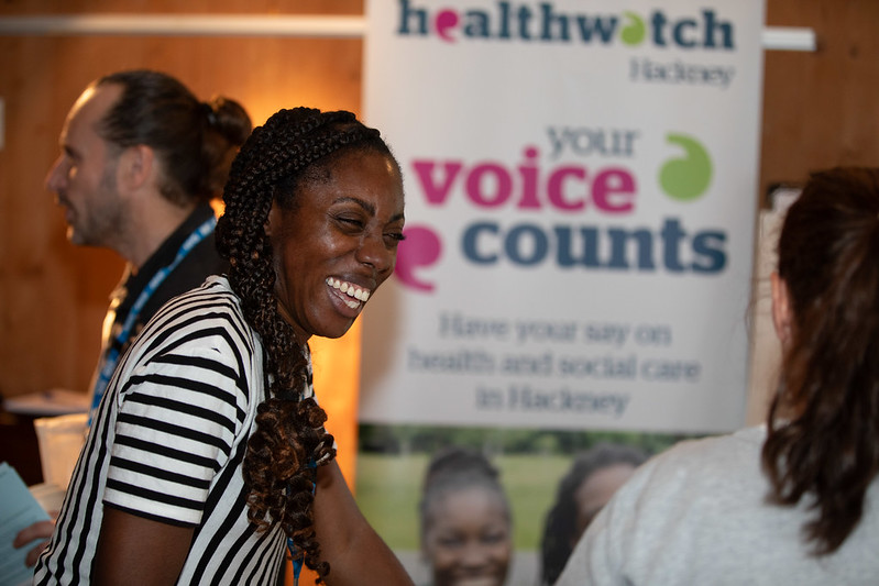 Woman laughing with a Healthwatch banner in the background