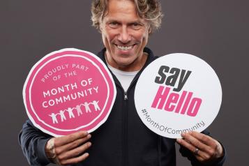 a man holds two signs that say "say hello"