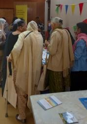 a group of women huddle round a table to read some information leaflets.