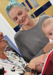 A Healthwatch Dudley volunteer talks to a woman and her baby in a waiting room