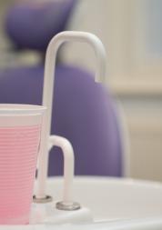Cup of pink mouthwash on sink in dental practice