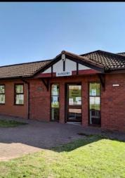 Photo of castle meadows surgery. Single story building with grass in front and blue skies above.